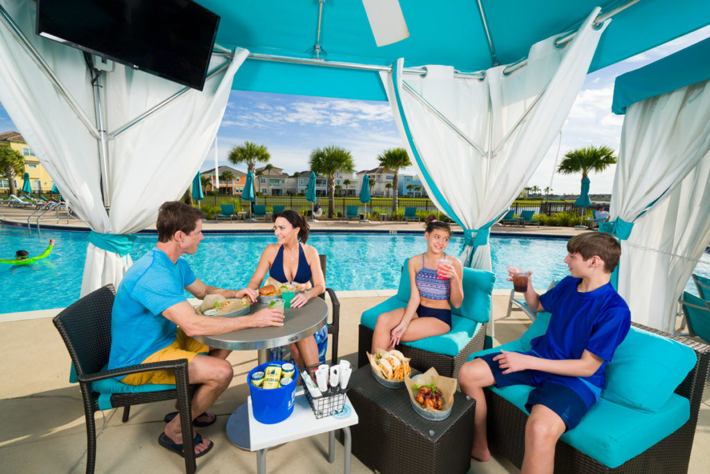 Family of a mom, dad, and two children sharing snacks and drinks under a private cabana at Margaritaville Resort Orlando.