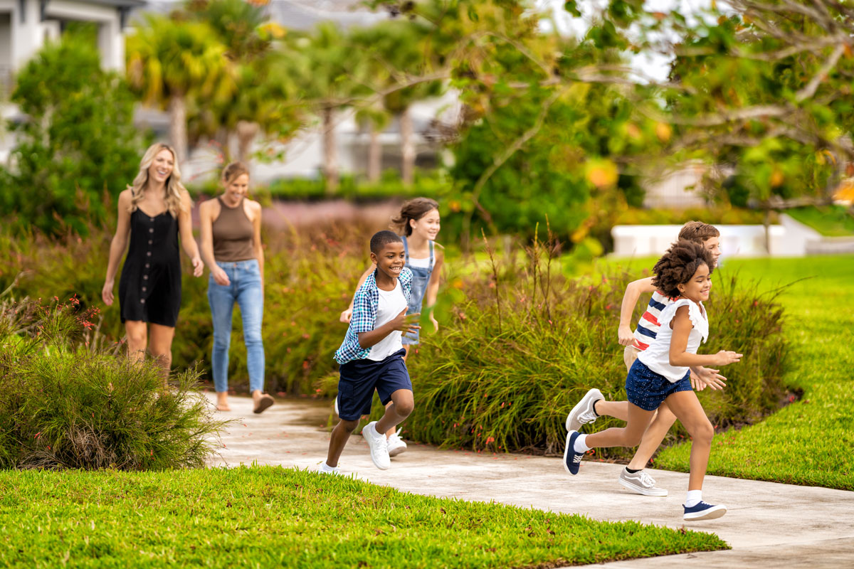 Kids running and playing outside their vacation home at The Bear’s Den Resort Orlando as their mothers watch.